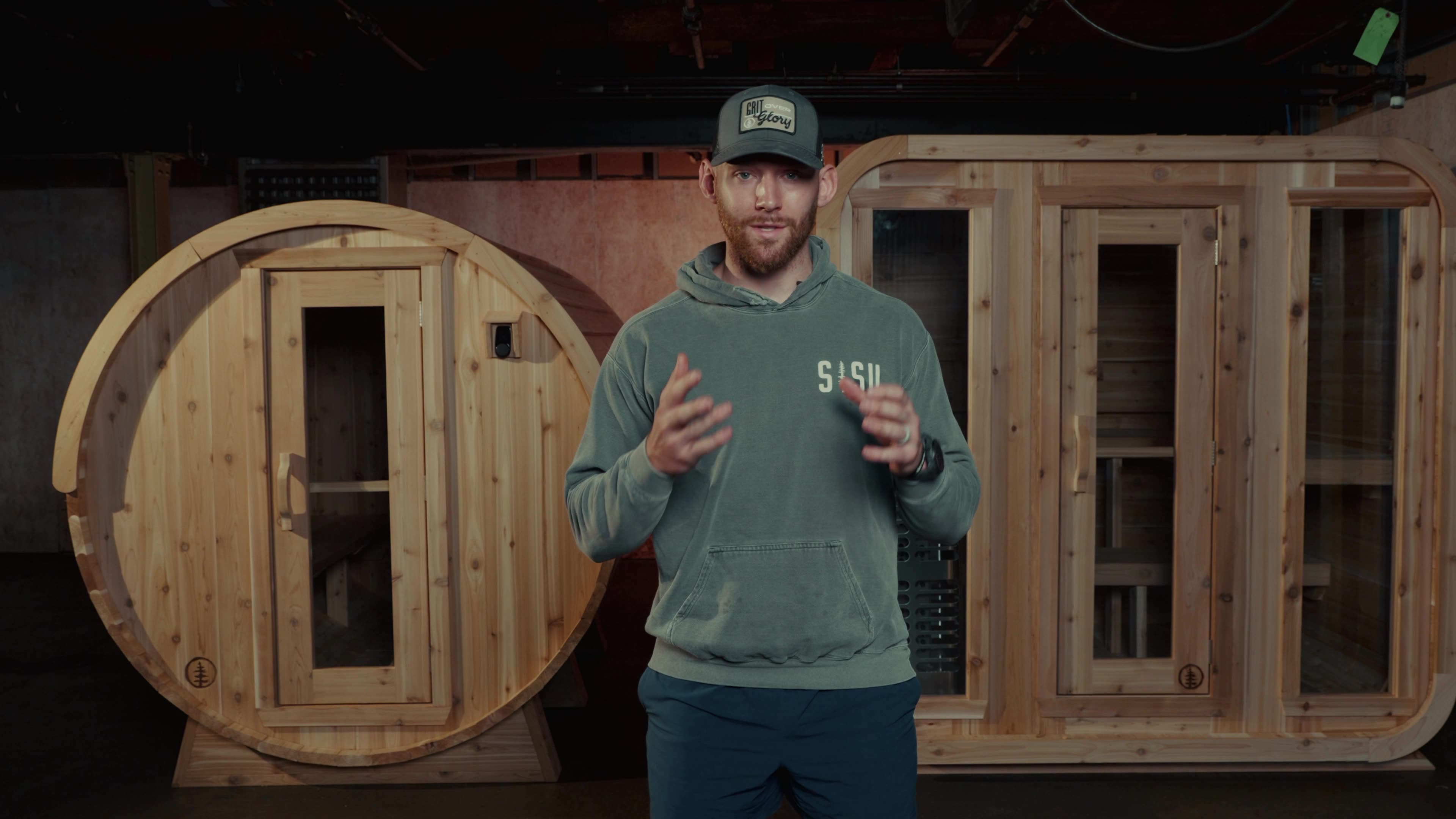Pete Nelson II standing between a SISU barrel sauna and cabin sauna